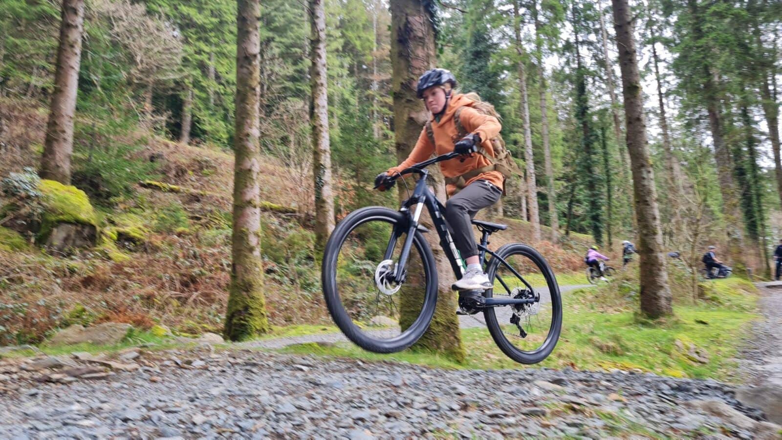 Girl mountain biking along forest path