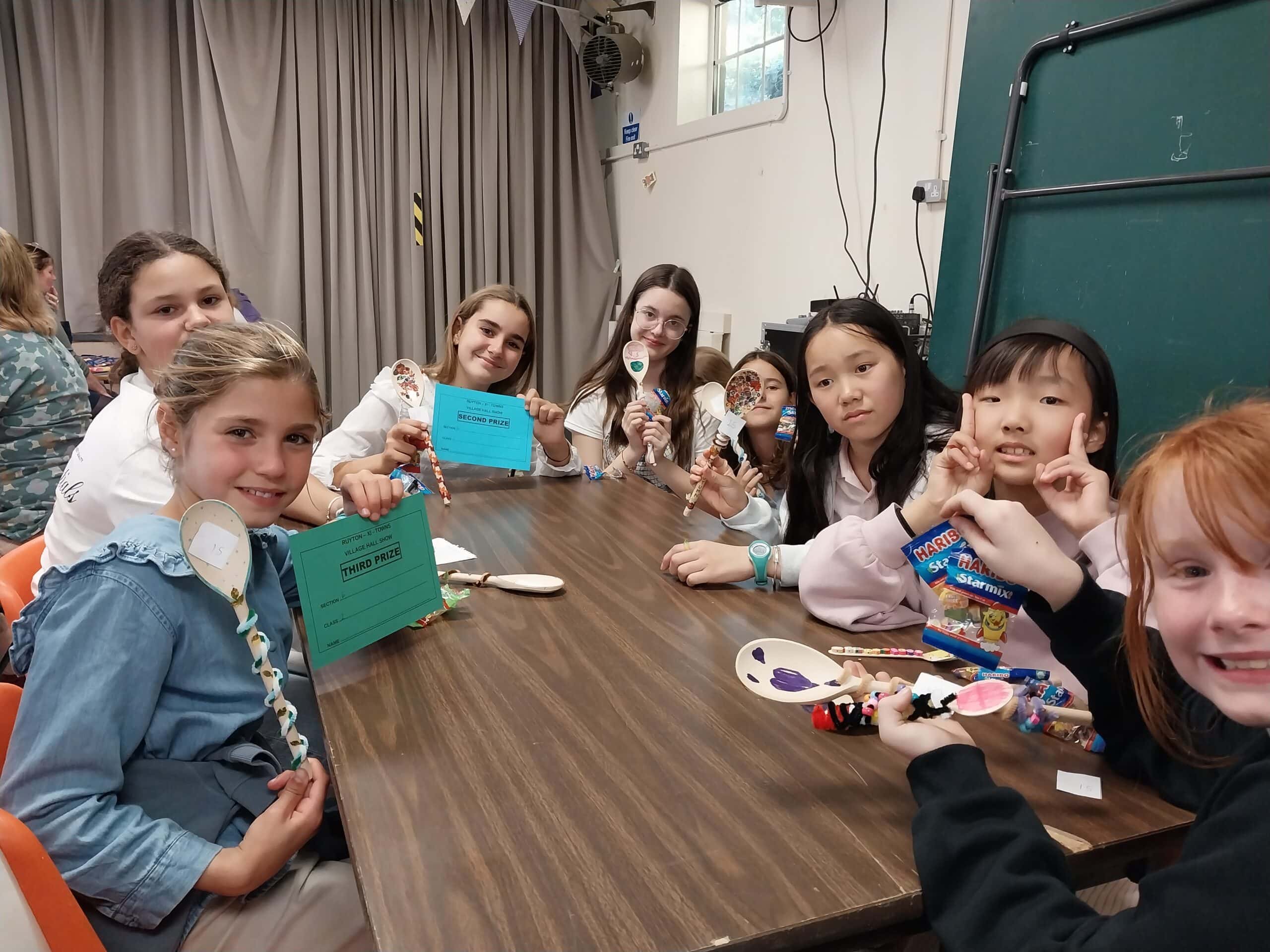 Girls sat around table with decorated wooden spoons