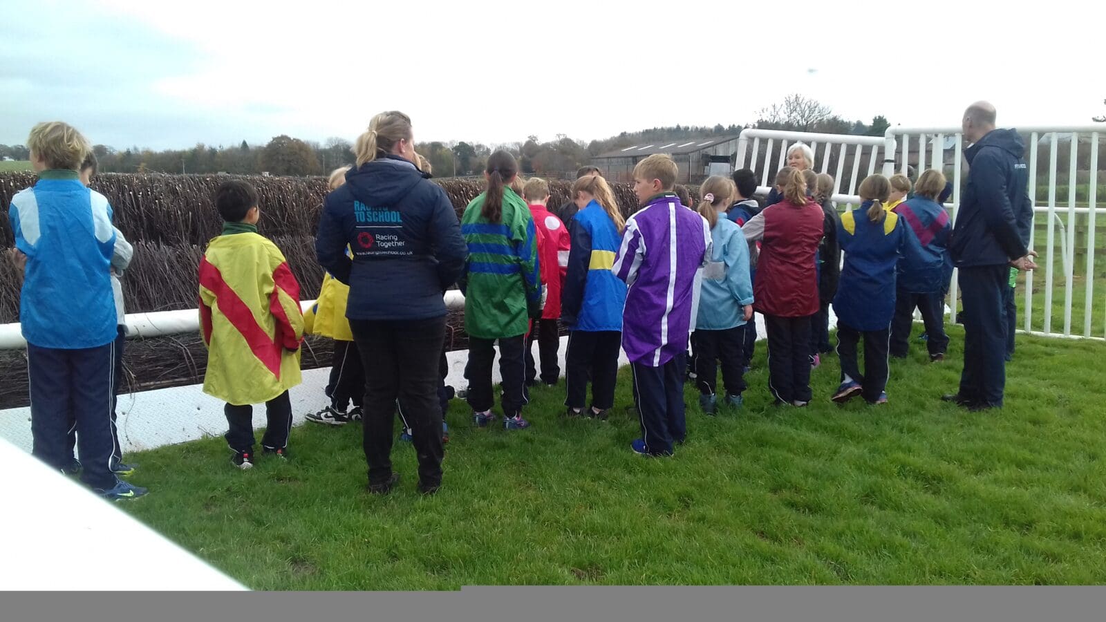 Group of school children on a racecourse looking at fences