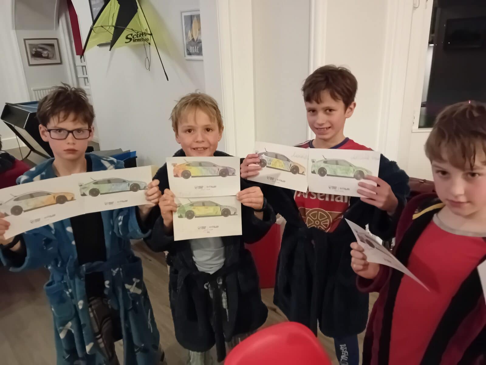 Boys in boarding common room showing drawings of racing cars