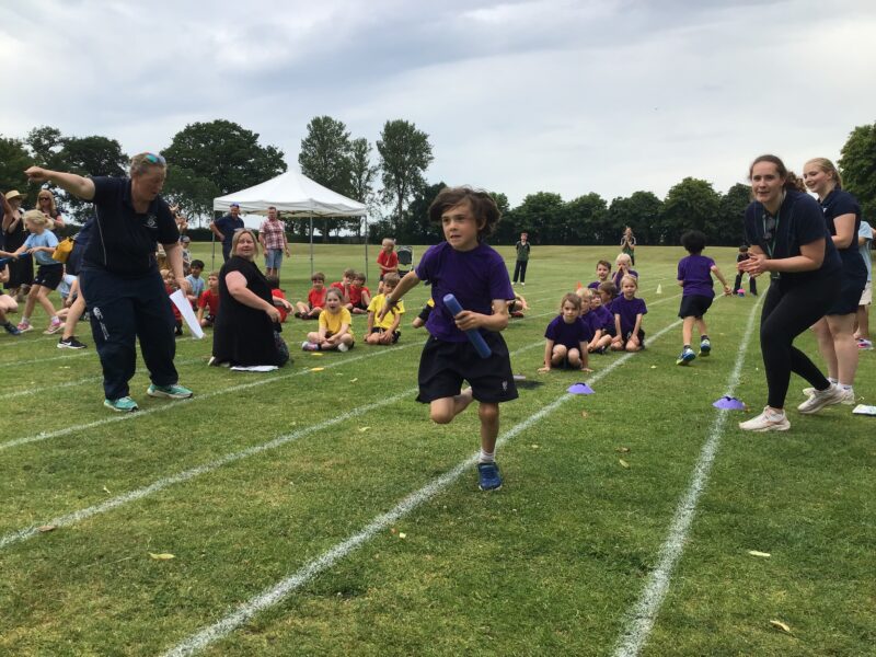 Young child competing in school relay race on grass track