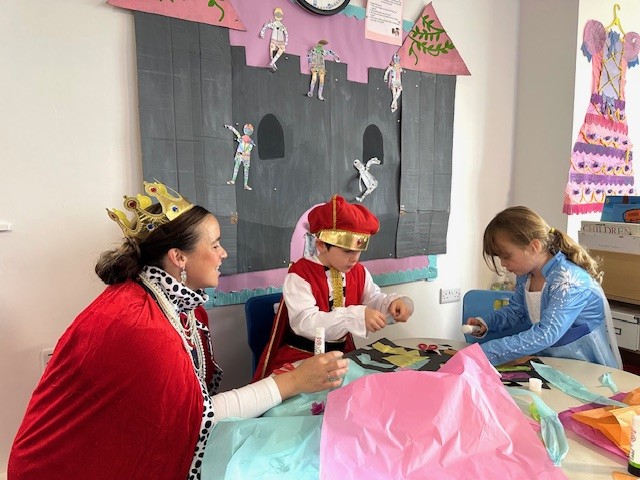 A teacher and children dressed up as medieval characters in a vibrant classroom