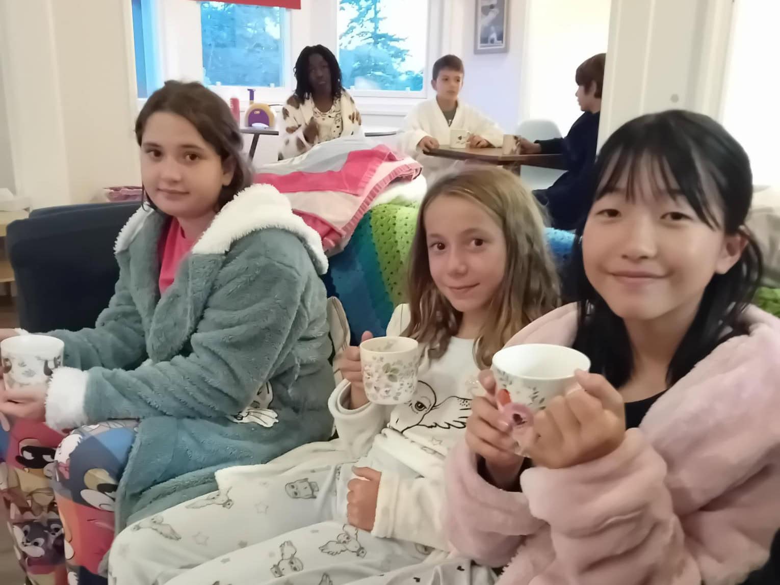 Three girls in dressing gowns drinking hot chocolate