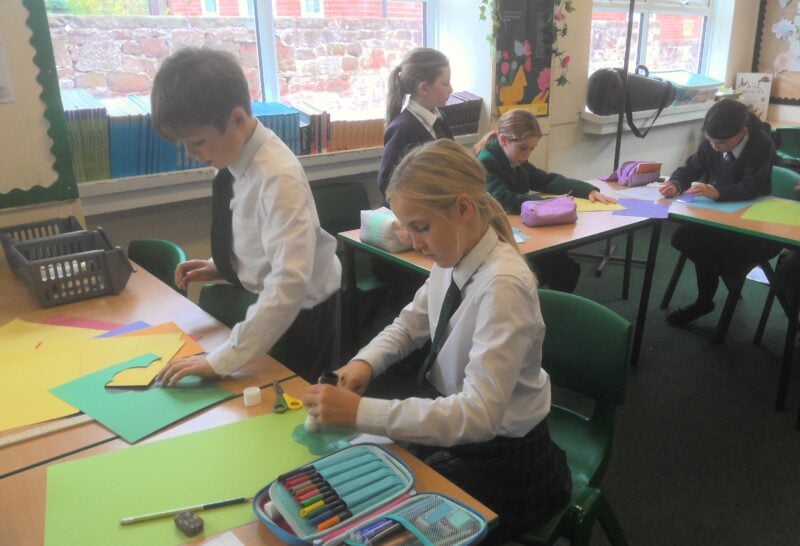 Children in a classroom working on brightly coloured paper
