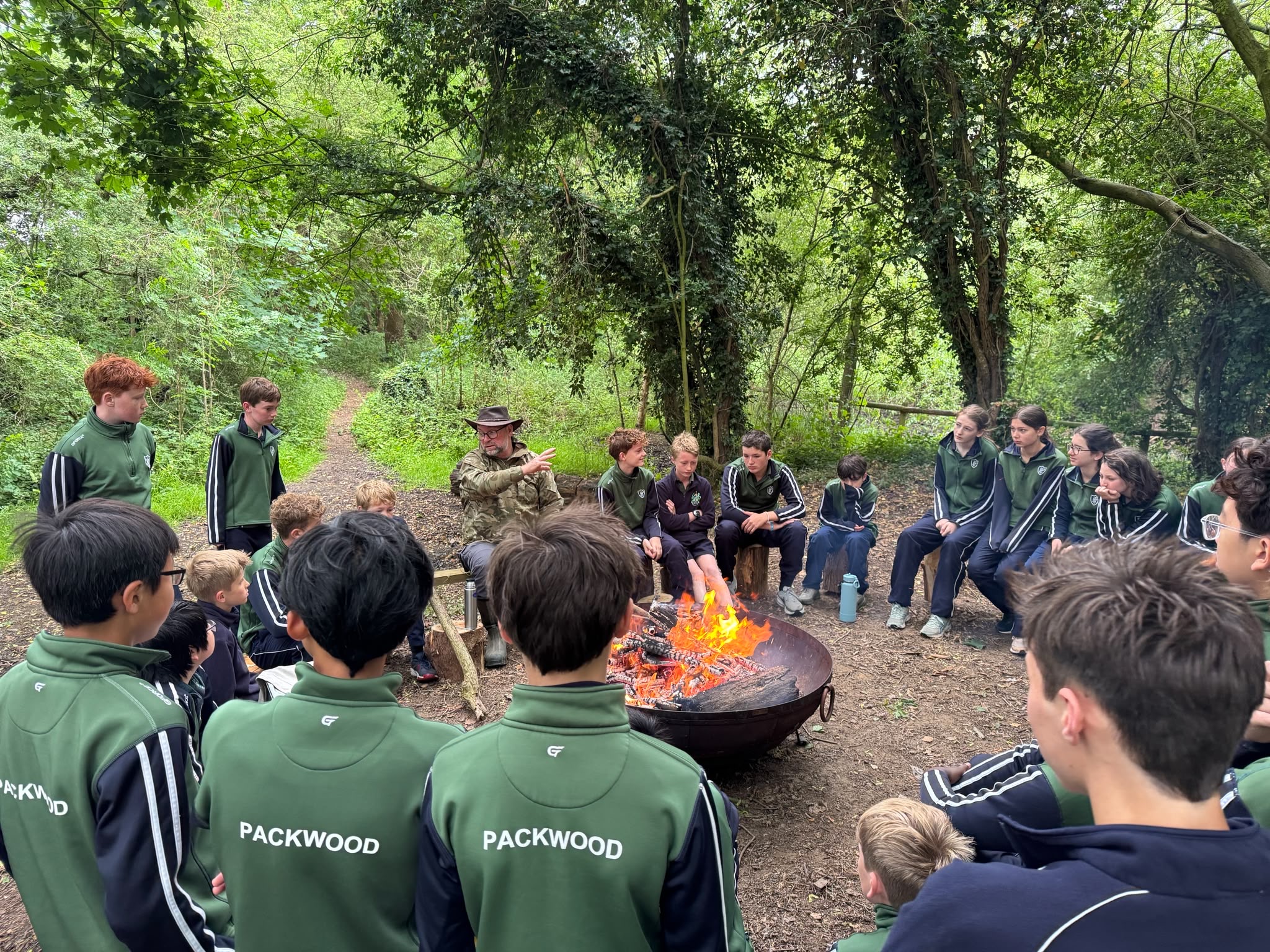 School children sat around campfire in Packwood jumpers