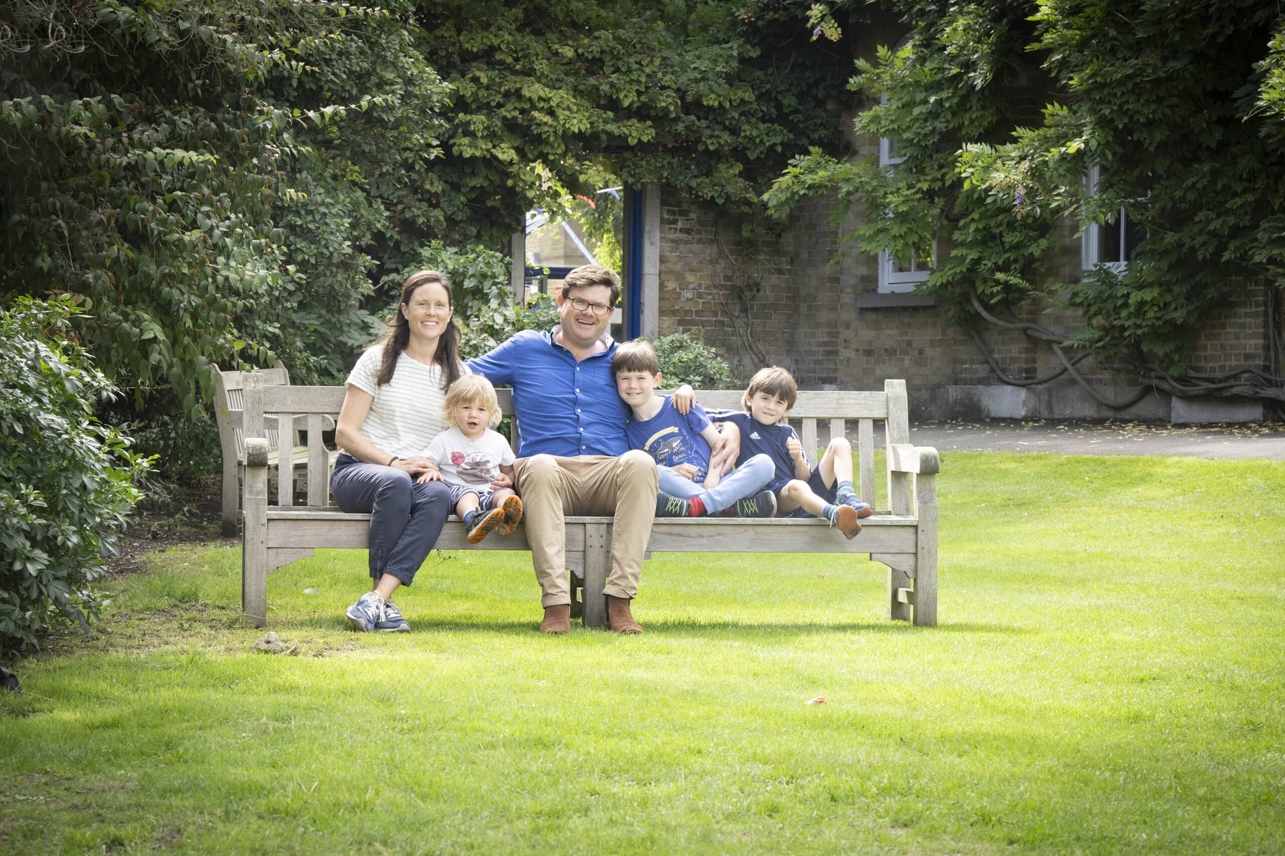 Headmaster sitting with family on a bench outside