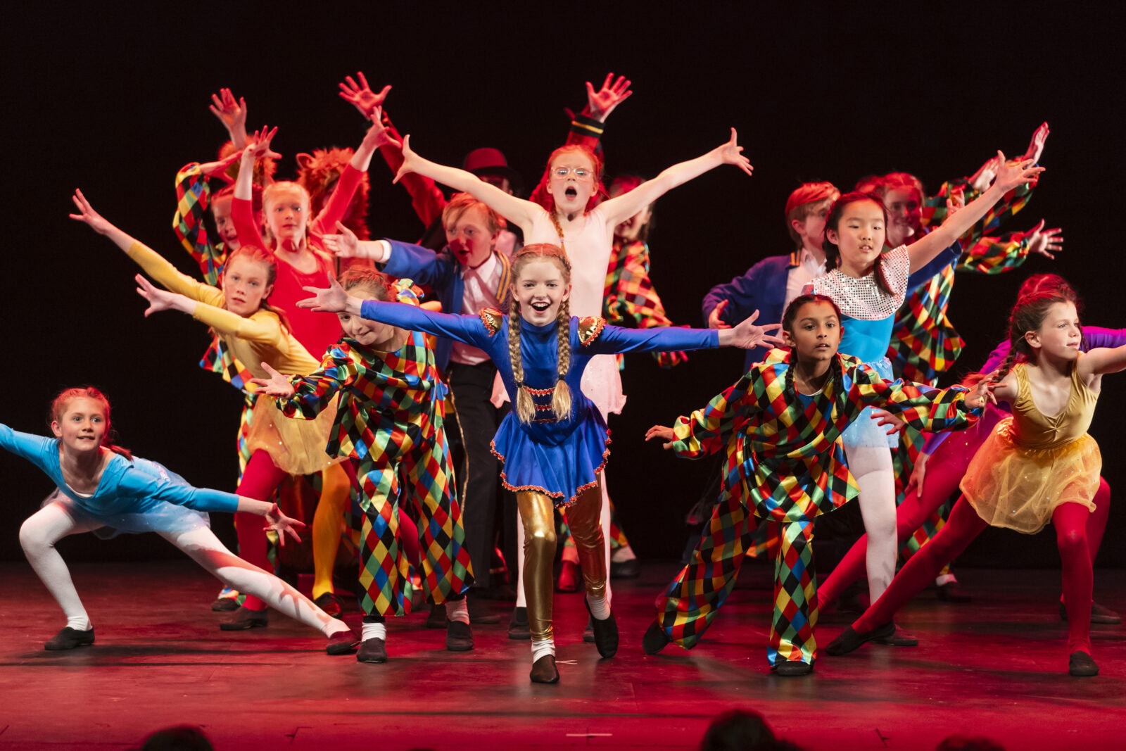 A group of dancers performing on stage in vibrant costumes