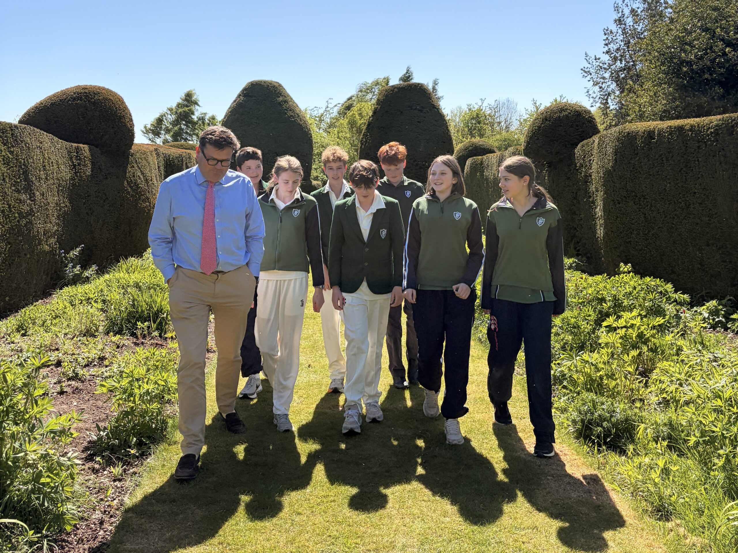 Pupils and Headmaster walking along lawn in beautiful school grounds