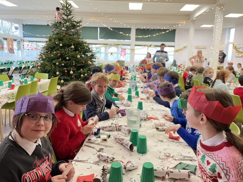 Children enjoying Christmas lunch in their festive themed school dining hall