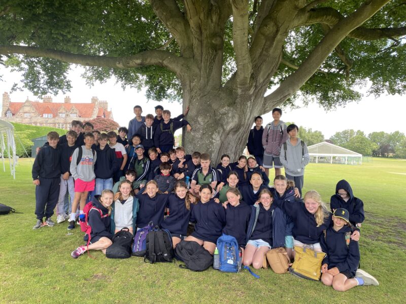 Group of children with rucksacks standing beneath a beautiful tree