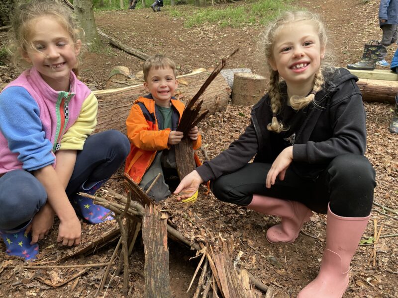 Three young children building a den