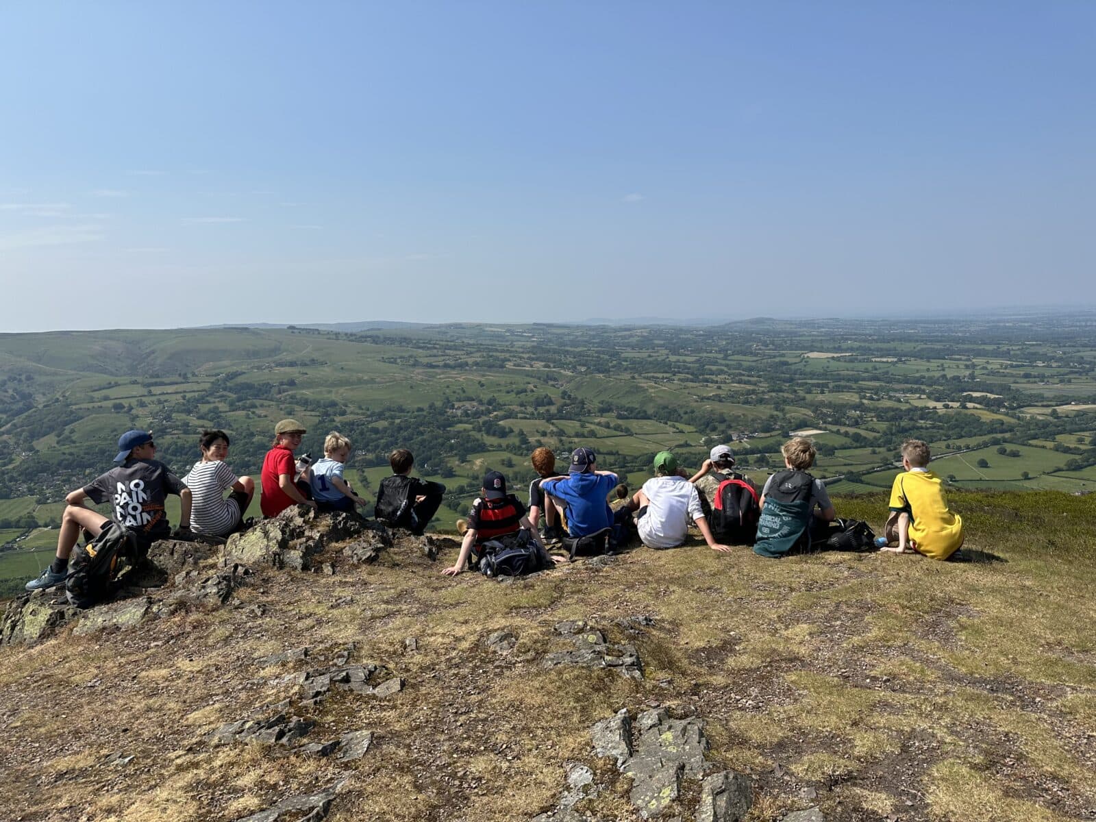 Group of school children sitting at the top of a hill admiring the view