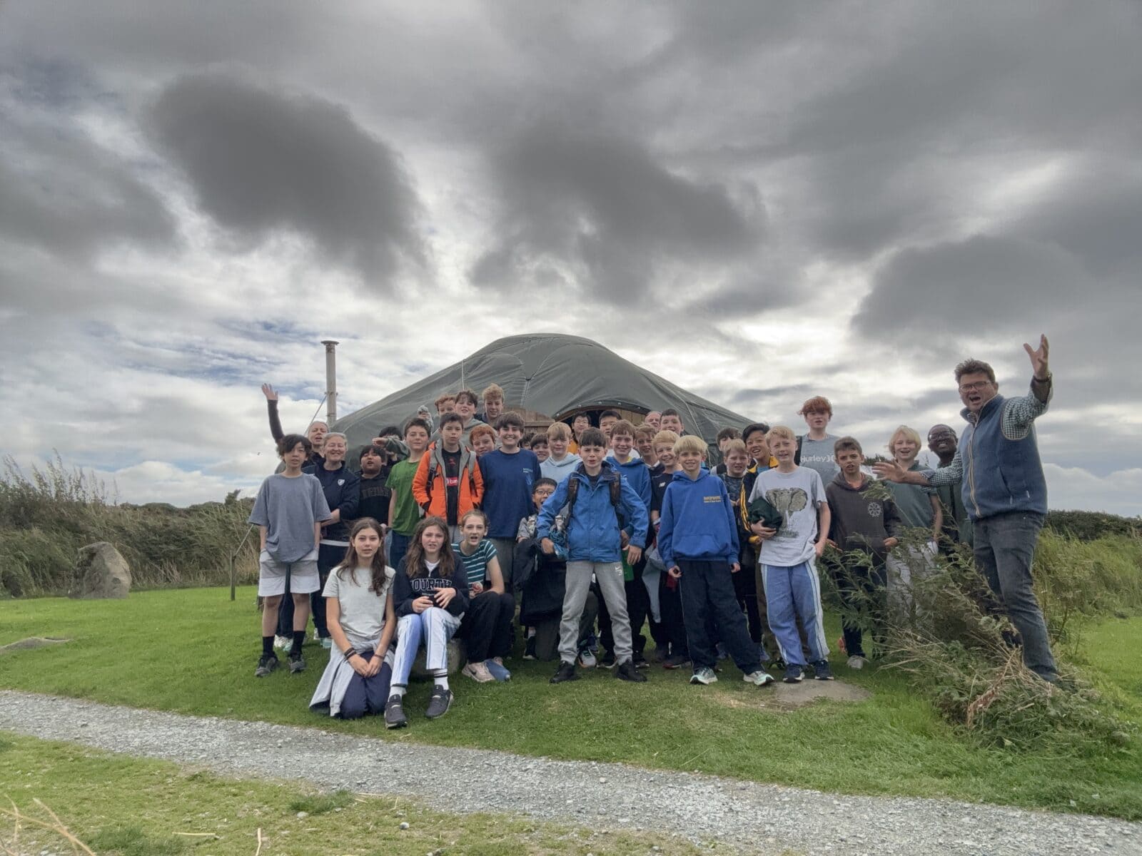 Large group of pupils and staff standing outside a large tent in windy weather