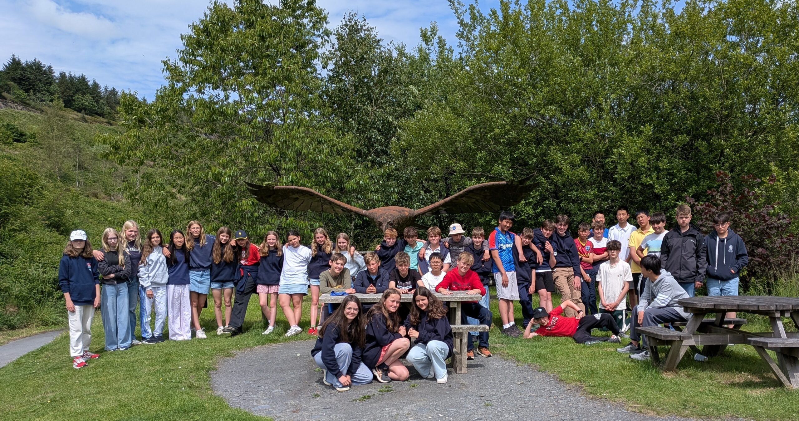 A group of school children in front of a large sculpture of a bird
