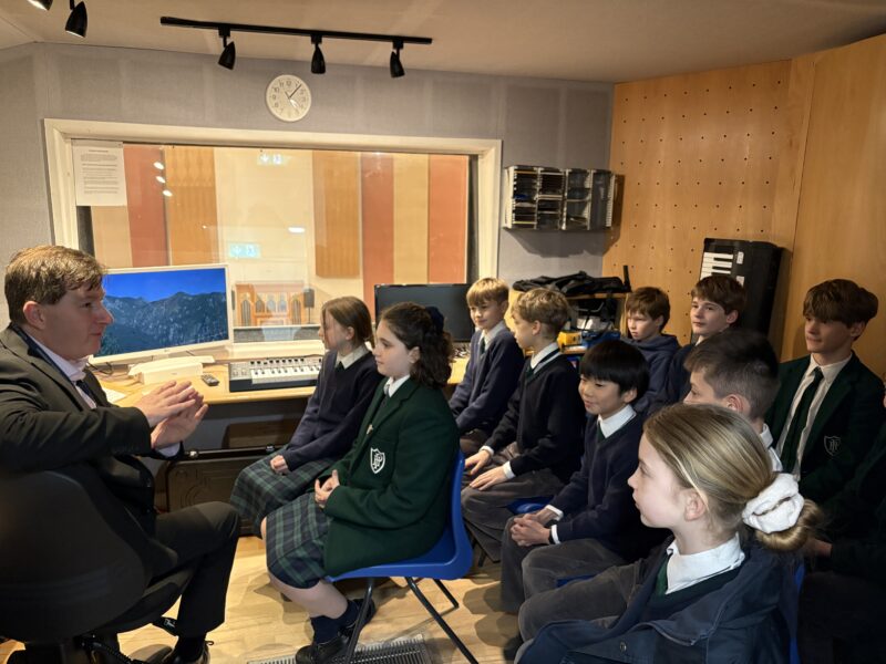 Children in a music booth listening to teacher