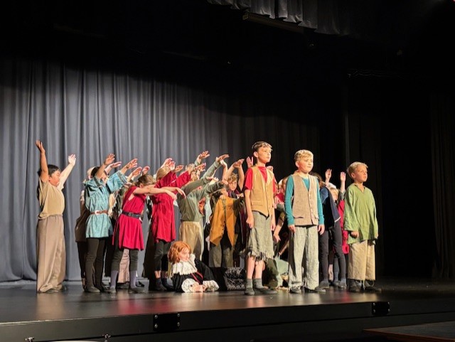 Group of young children performing on school theatre stage