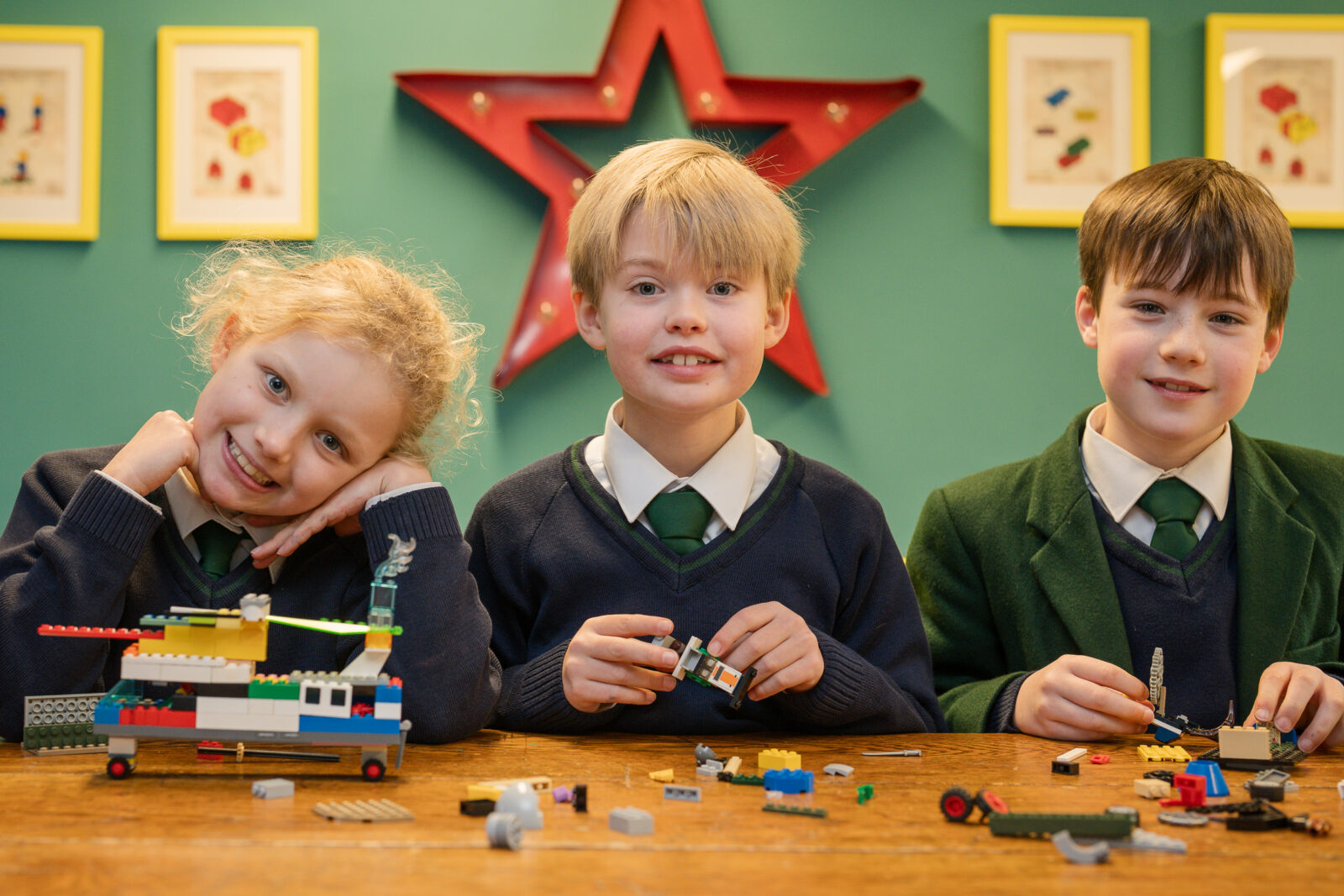 Three happy school children building lego