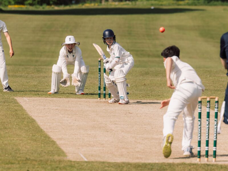 A cricket match with close up of bowler, batsman and wicket keeper