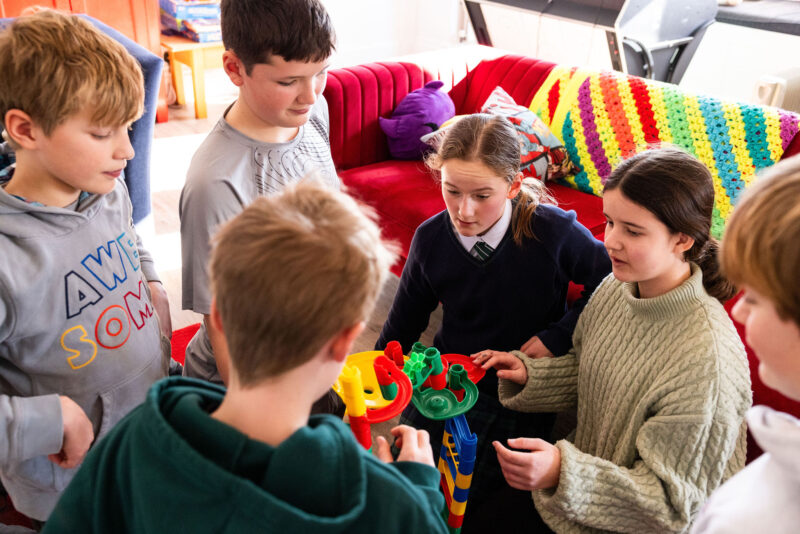 Boys and girls constructing model together in school boarding house