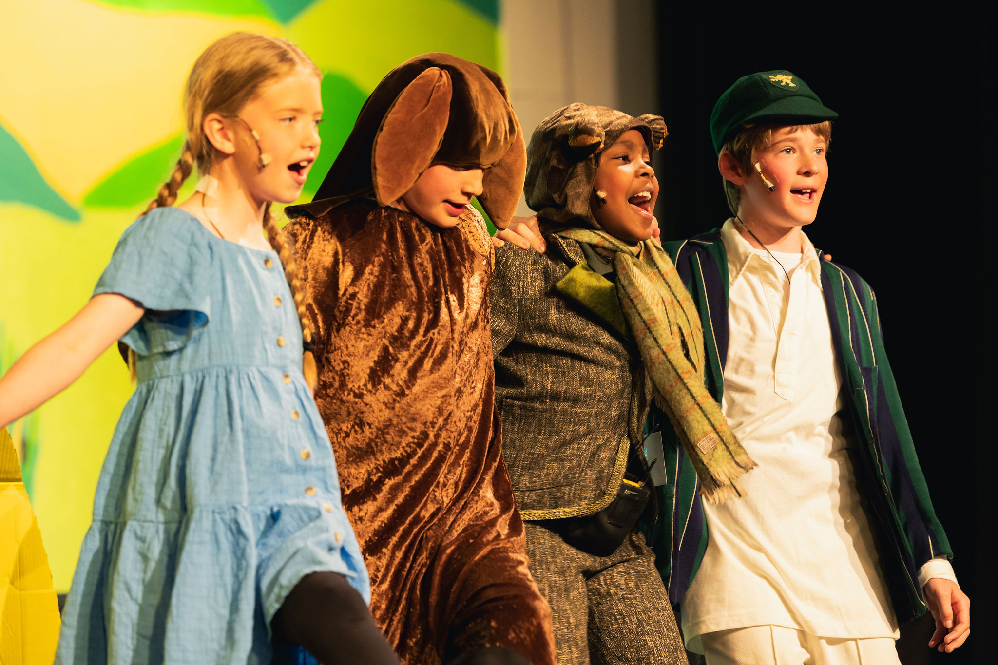 Four children on stage smiling and performing