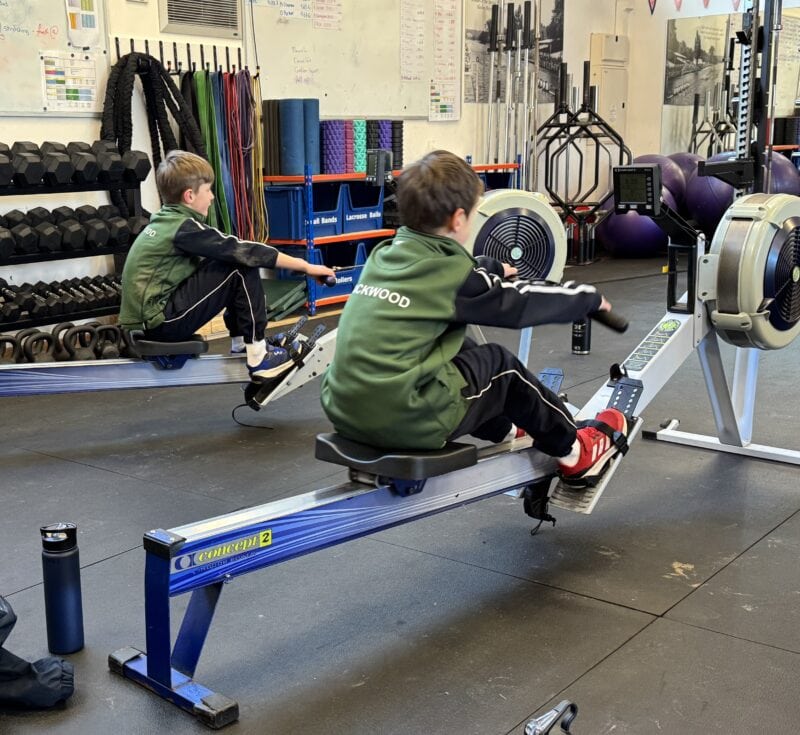 Two boys rowing on ergos