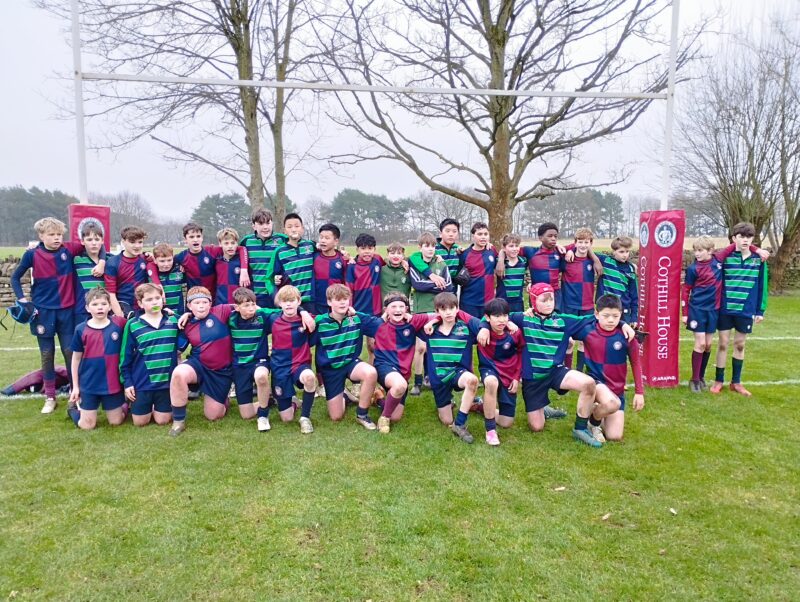 Two school rugby teams joining together for a team photograph on a school rugby pitch