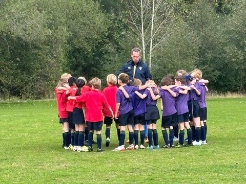 Coach with two teams of school fooball players wearing house colours