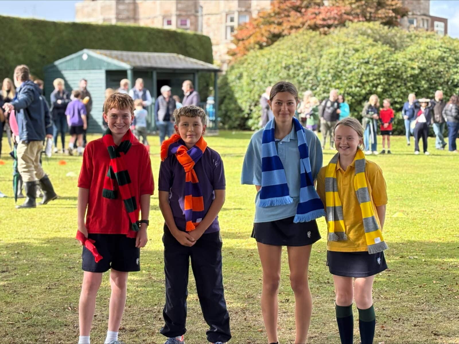 Two girls and two boys wearing different coloured scarves to represent their houses at school