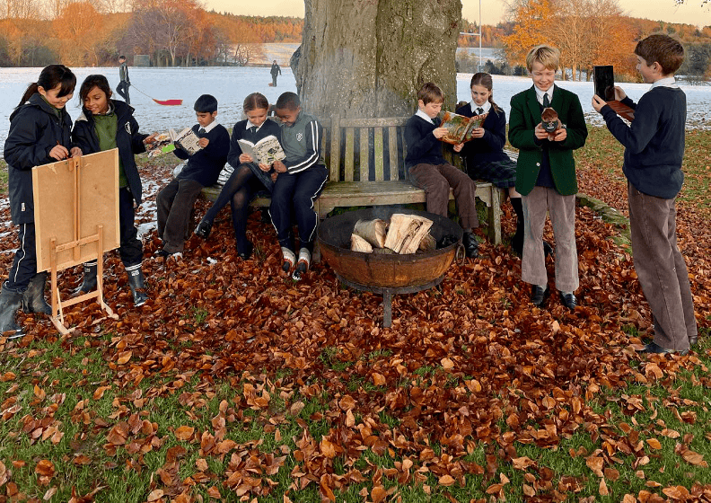 Children reading together around a tree with snowy backdrop