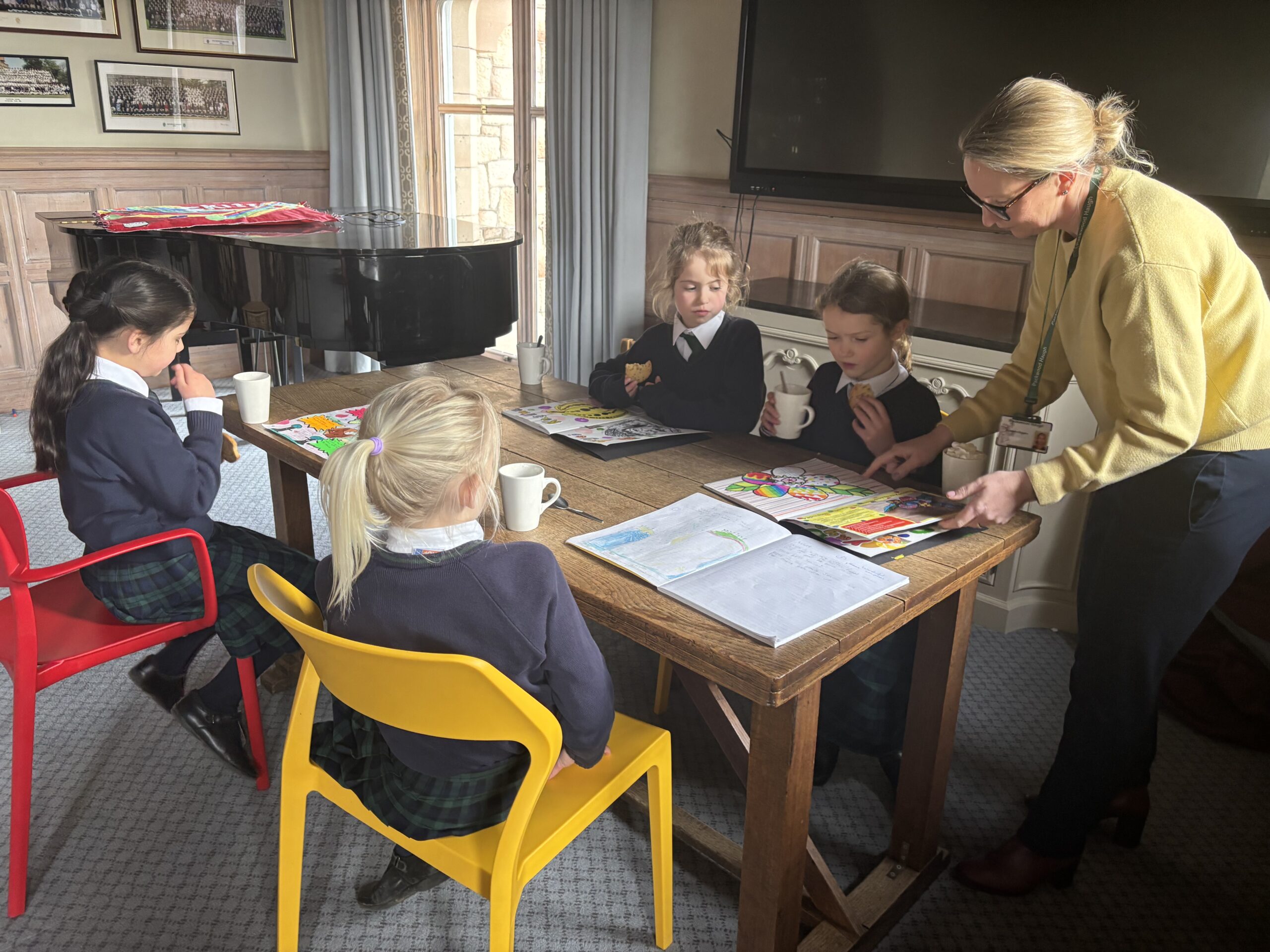 Children sat around table sharing work and drinking hot chocolates