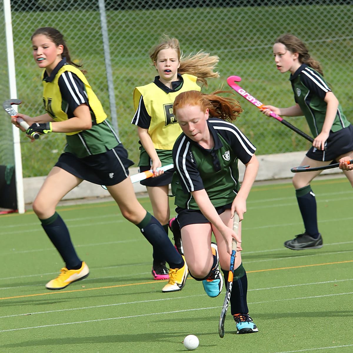 Girls playing hockey on astroturf pitch