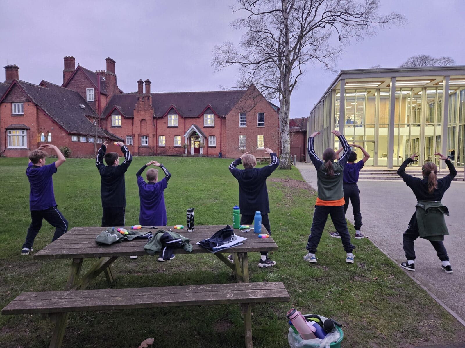 Pupils learning dance moves on a lawn within school grounds