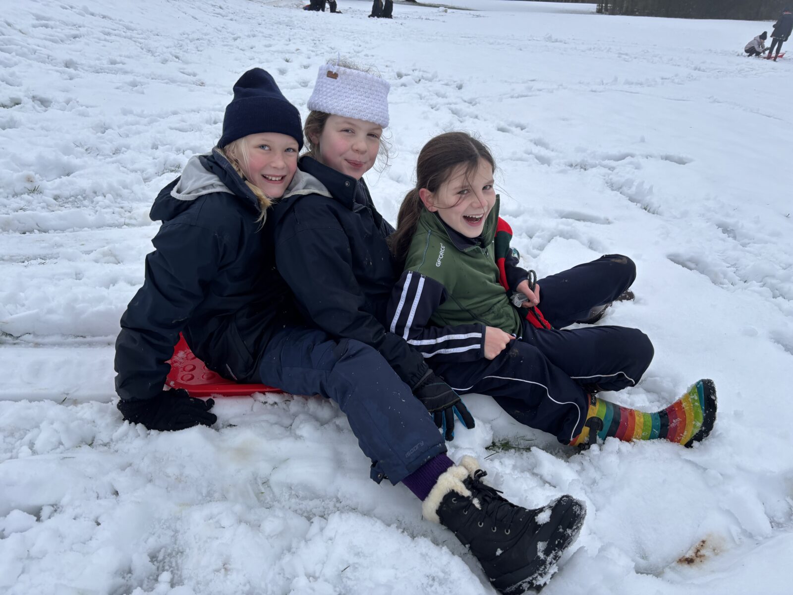 Girls smiling and laughing on a sledge in the snow