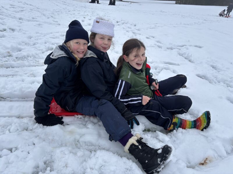 Girls smiling and laughing on a sledge in the snow